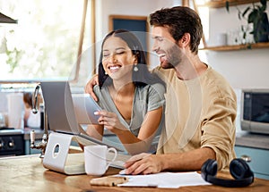 Happy young interracial couple calculating their budget using wireless devices at home. Smiling young caucasian man