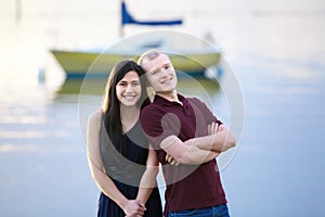 Happy young interracial couple standing together by lake