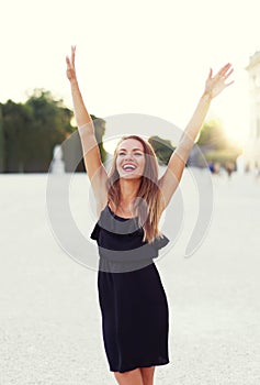 Happy young joyful carefree woman hands up in park