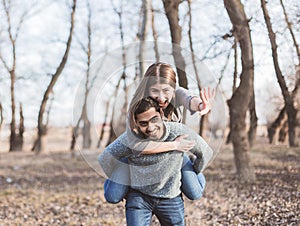 Happy young joyful couple having fun piggybacking laughing together in the autumn