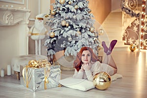 Young lady with curlu hair gifts by the fireplace near the Christmas tree. New year concept