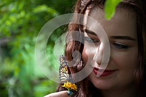 A happy lady / girl holding a flower with a butterfly sitting on it