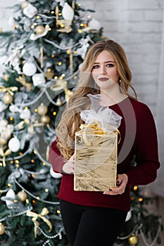 Happy young lady with long hair gifts by the fireplace near the Christmas tree