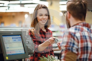 Happy young lady standing near cashier`s desk photo