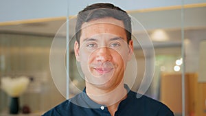 Happy young latin business man leader standing in office, close up portrait.