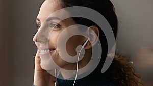 Happy young latin female listening to song in wired earphones