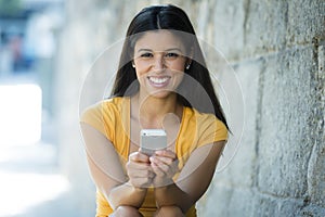 Happy young latin woman talking and texting on smart phone