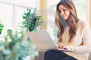 Happy young latina woman using her laptop at home