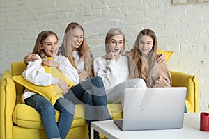 Happy young lesbian couple with daughters in casual clothes sitting together on yellow sofa at home