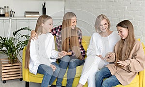 Happy young lesbian couple with two beautiful daughters with long hair, all dressed casual