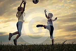 Happy young little boy and girl playing in the field with socce