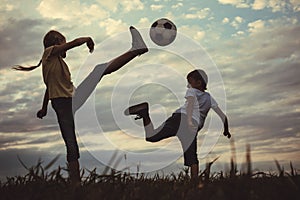 Happy young little boy and girl playing in the field  with soccer ball