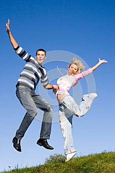 Happy Young love Couple - jumping under blue sky