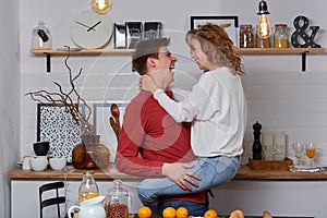 Happy young lovely couple on kitchen hugging each other. They enjoy spending time togehter