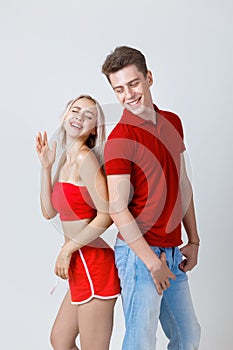 Happy young lovely couple standing back to back and smiling looking at camera on white background