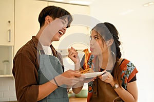 Happy young lovers eating bolognese spaghetti in kitchen. Love, relationships and food concept