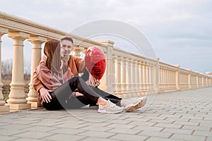 Young loving couple embracing each other outdoors in the park holding balloons