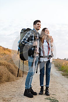 Happy young loving couple outside with backpack in free alternative vacation camping