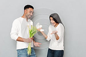 Happy young loving couple standing over grey wall