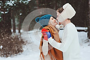 happy young loving couple walking in snowy winter forest, covered with snow