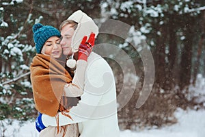 Happy young loving couple walking in snowy winter forest, covered with snow