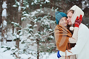 Happy young loving couple walking in snowy winter forest, covered with snow