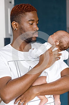 Happy young loving father holding newborn son child and laughing. Afro American caring father looking at baby son. Child