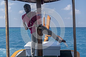 Happy Young maldivian man portrait while driving boat with feet