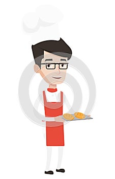 Happy young male baker holding tray of bread.