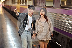 Happy young male and female tourist walking with a luggage walking at railroad station platform