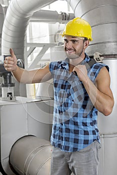 Happy young male worker gesturing thumbs up in industry
