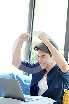Happy young man arms up while working with laptop computer at home, Positive emotion when working at home