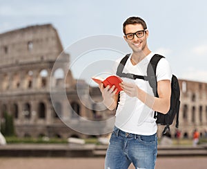 Happy young man with backpack and book travelling