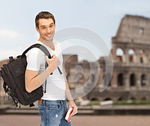 Happy young man with backpack and book travelling