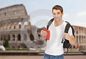 Happy young man with backpack and book travelling