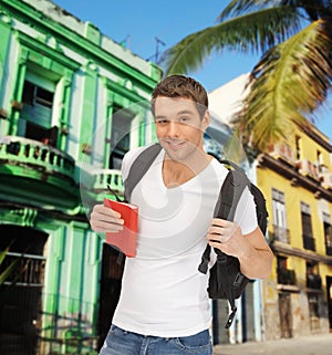 Happy young man with backpack and book travelling