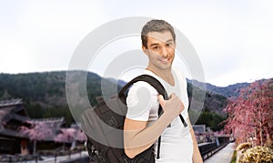 Happy young man with backpack and book travelling