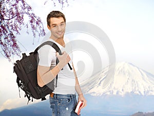 Happy young man with backpack and book travelling