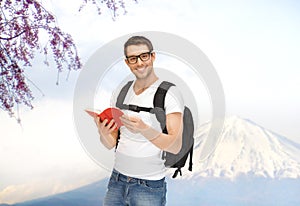 Happy young man with backpack and book travelling