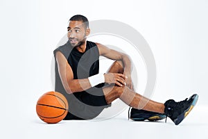 Happy young man basketball player sitting and looking away