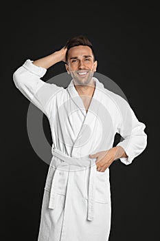 Happy young man in bathrobe on black