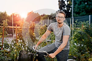 Happy young man with bicycle in park. With glasses for sight at sunset.