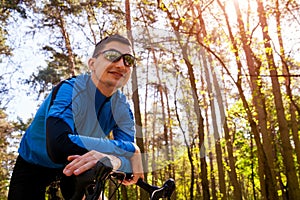 Happy young man bicyclist riding a road bike in spring forest. Man having rest