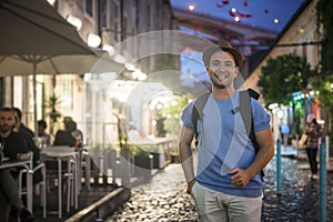 Happy young man in blue shirt walking on in the city at the evevning photo