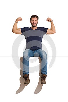 Happy Handsome Man Is Sitting On A Top And Flexing Muscles