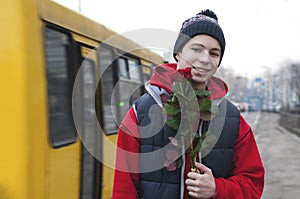 Happy young man with a bouquet of roses on a city street