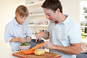 Happy young man with boy peeling vegetables