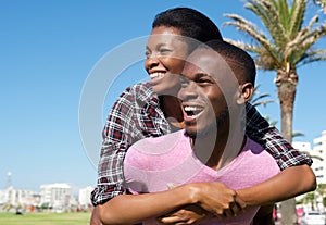 Happy young man carrying attractive girlfriend on his back