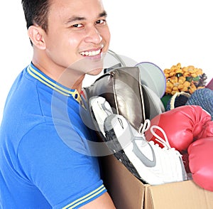 Happy young man carrying box full of stuff