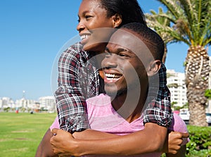 Happy young man carrying girlfriend on back